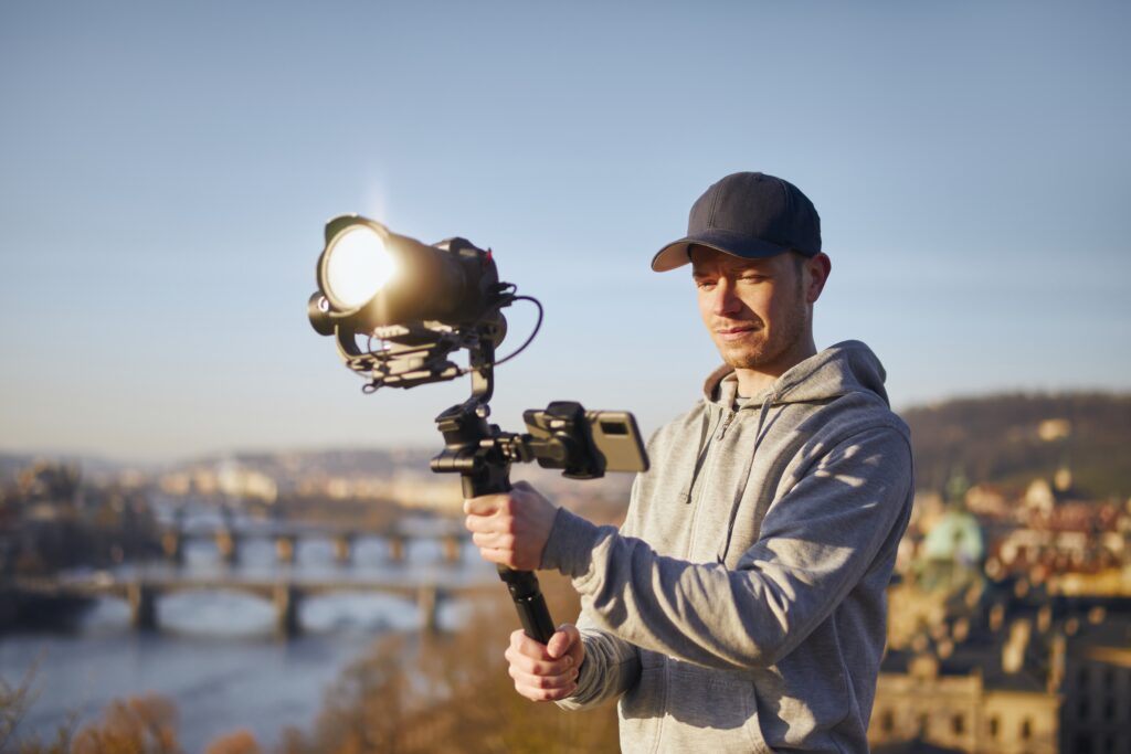 Man filming with camera and gimbal against urban skyline